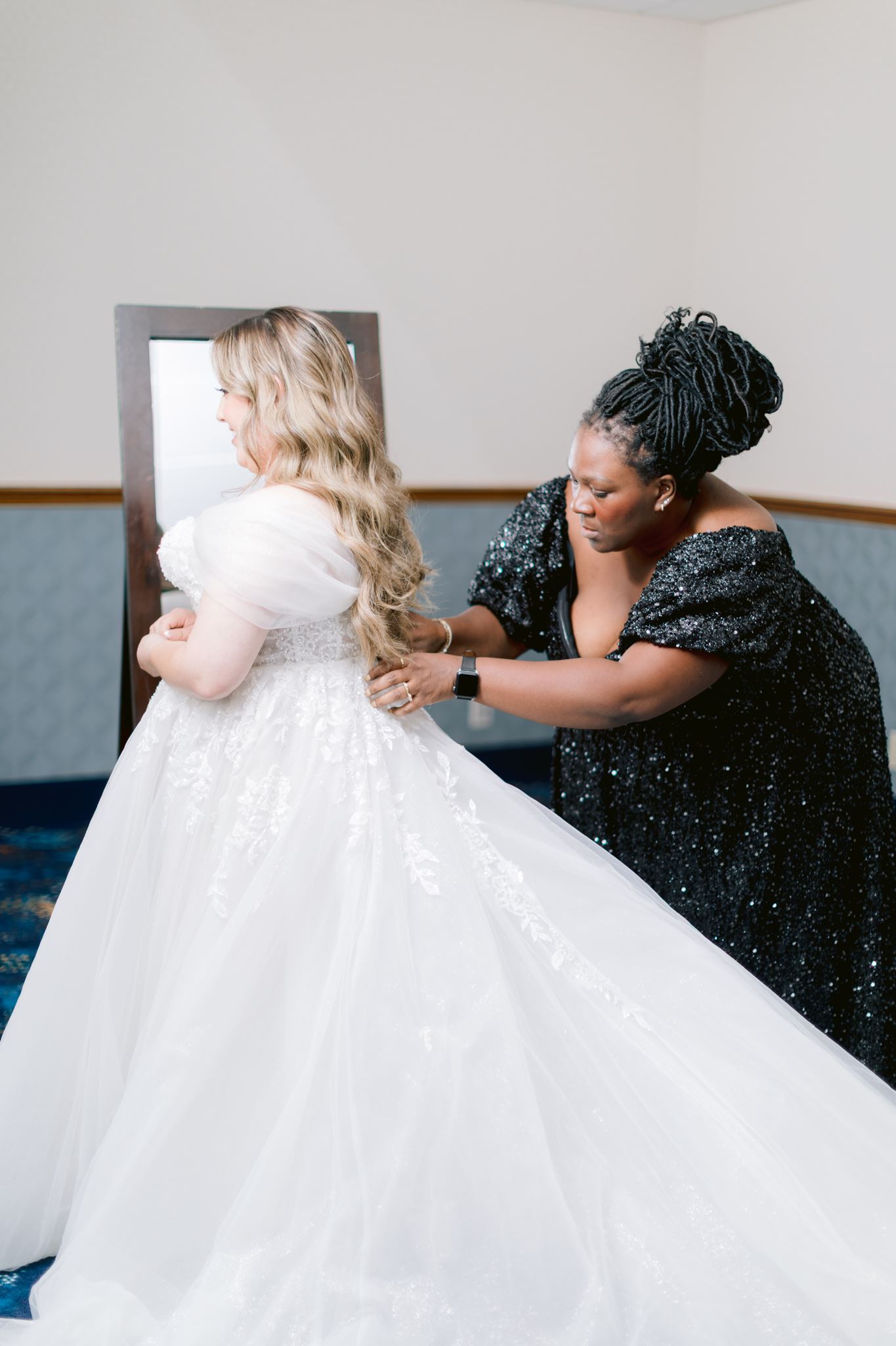 Erin assisting a bride with her wedding gown